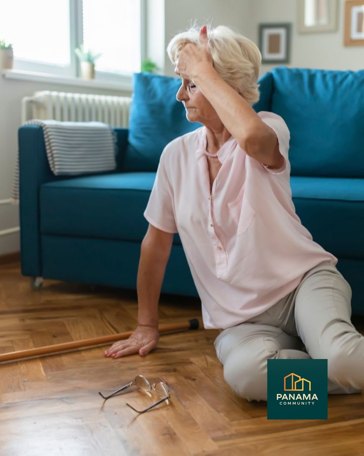 Ältere Frau sitzt nach einem Sturz auf dem Boden im Wohnzimmer, Gehstock und Brille liegen neben ihr. Sie wirkt nachdenklich und versucht, sich wieder aufzurichten.