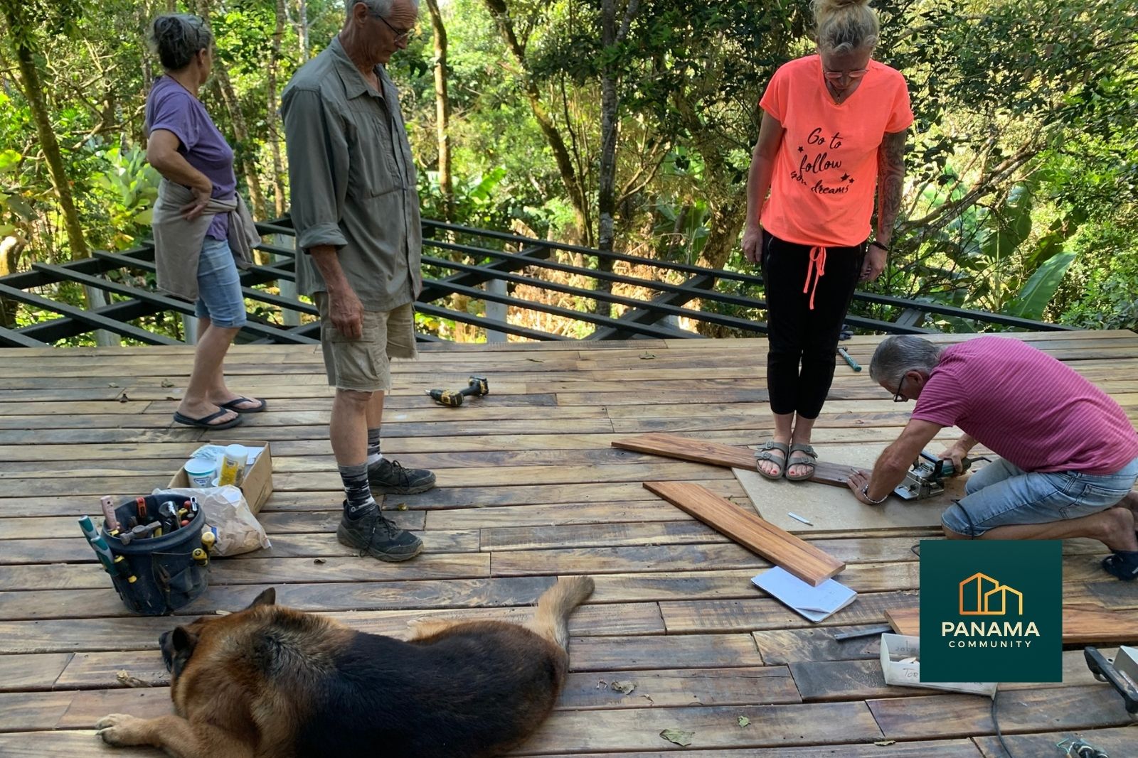 Mehrere Menschen arbeiten gemeinsam an einer Holzterrasse im Grünen, gemeinschaftlicher Aufbau der Panama Community Refugio Palmira
