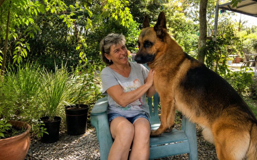 Frau mit Schäferhund in einem grünen Garten im Hochland von Panama